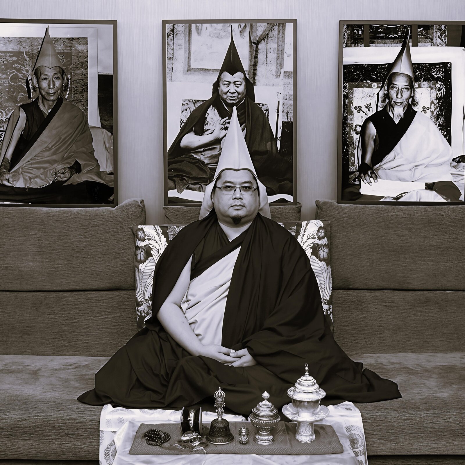H.E. Tsem Rinpoche seated in front of three black-and-white portraits of his Gelugpa lineage masters.