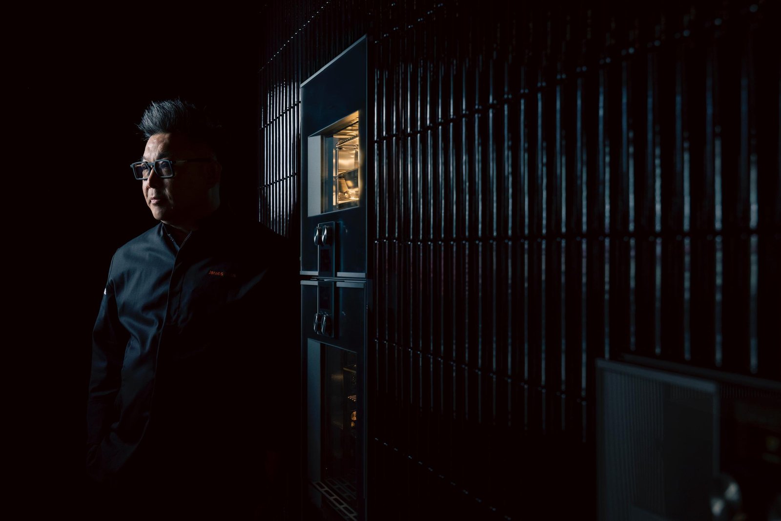 James Won in profile beside an illuminated Gaggenau 400 series combi oven at Inspiration Haus &mdash; a cinematic, low-light atelier portrait.