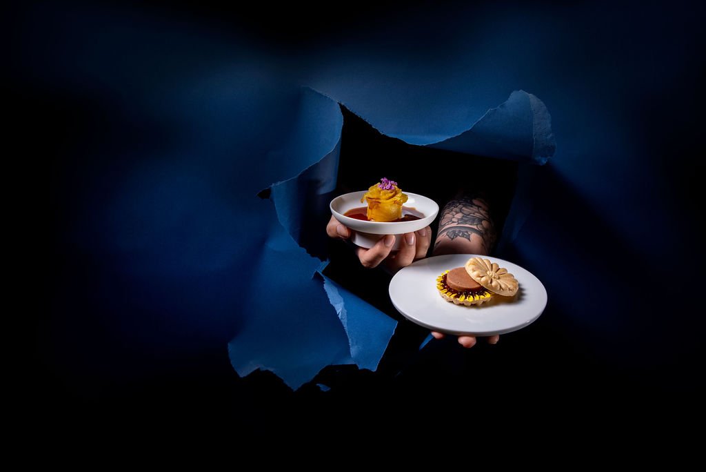 Two small plates with canap&eacute;s held through torn dark-blue paper.