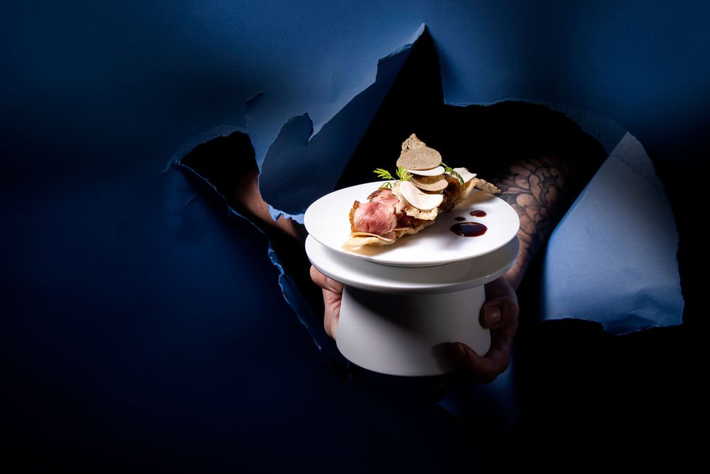 A bowl course held to the light through torn dark-blue paper.