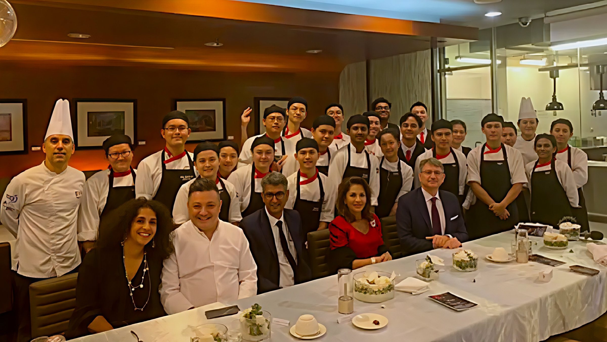 The students in whites standing behind the guests at the table at Truffles Restaurant