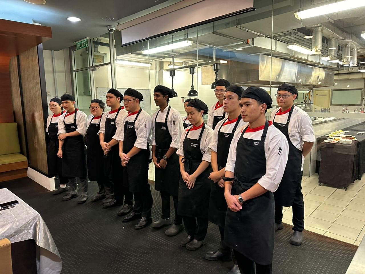 A graduating class of Taylor's culinary students lined up in whites in the kitchen