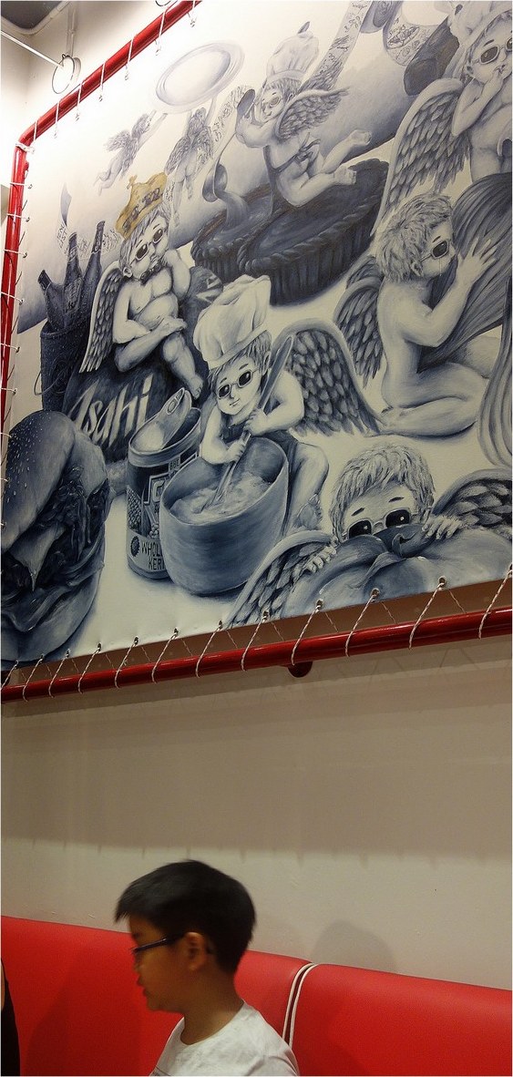 The cherub mural above a red booth: cherub cooks in sunglasses and chef's hats among burgers, pies and bottles, drawn in grey and blue.