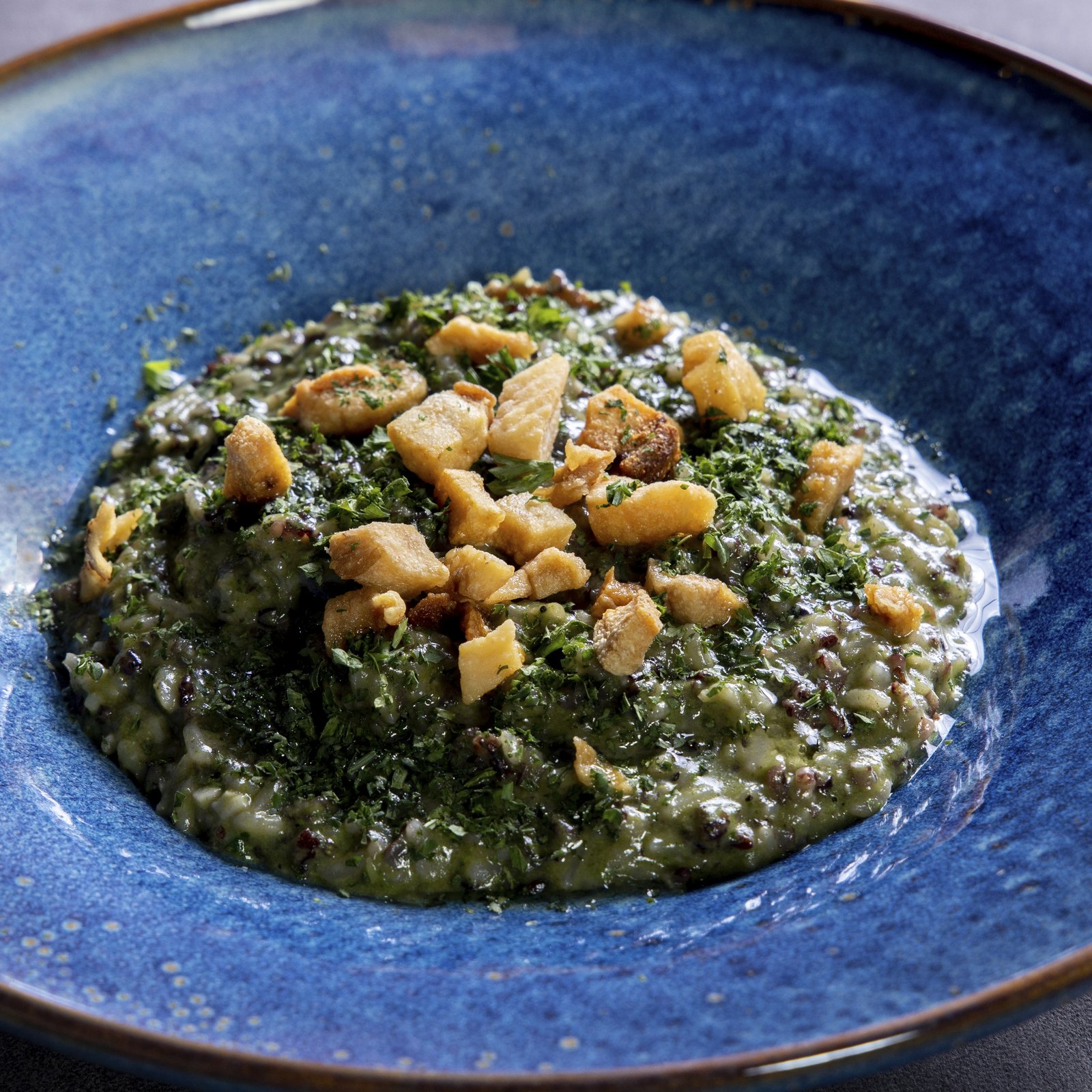 Bouchon Enfin herb risotto — Sarawak heritage rice cooked green with parsley and herbs, finished with crisp pork puffs.