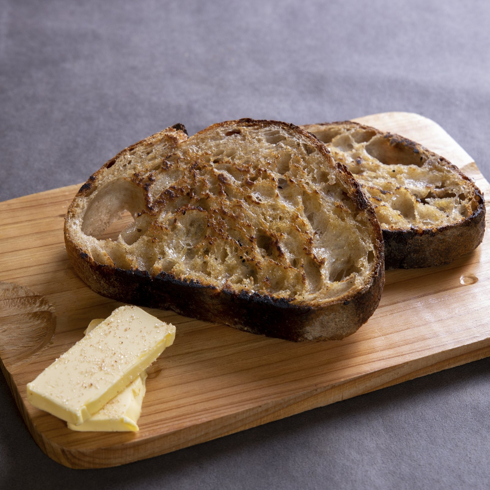 Bouchon Enfin opening — toasted sourdough on a wooden board with cultured butter beside.