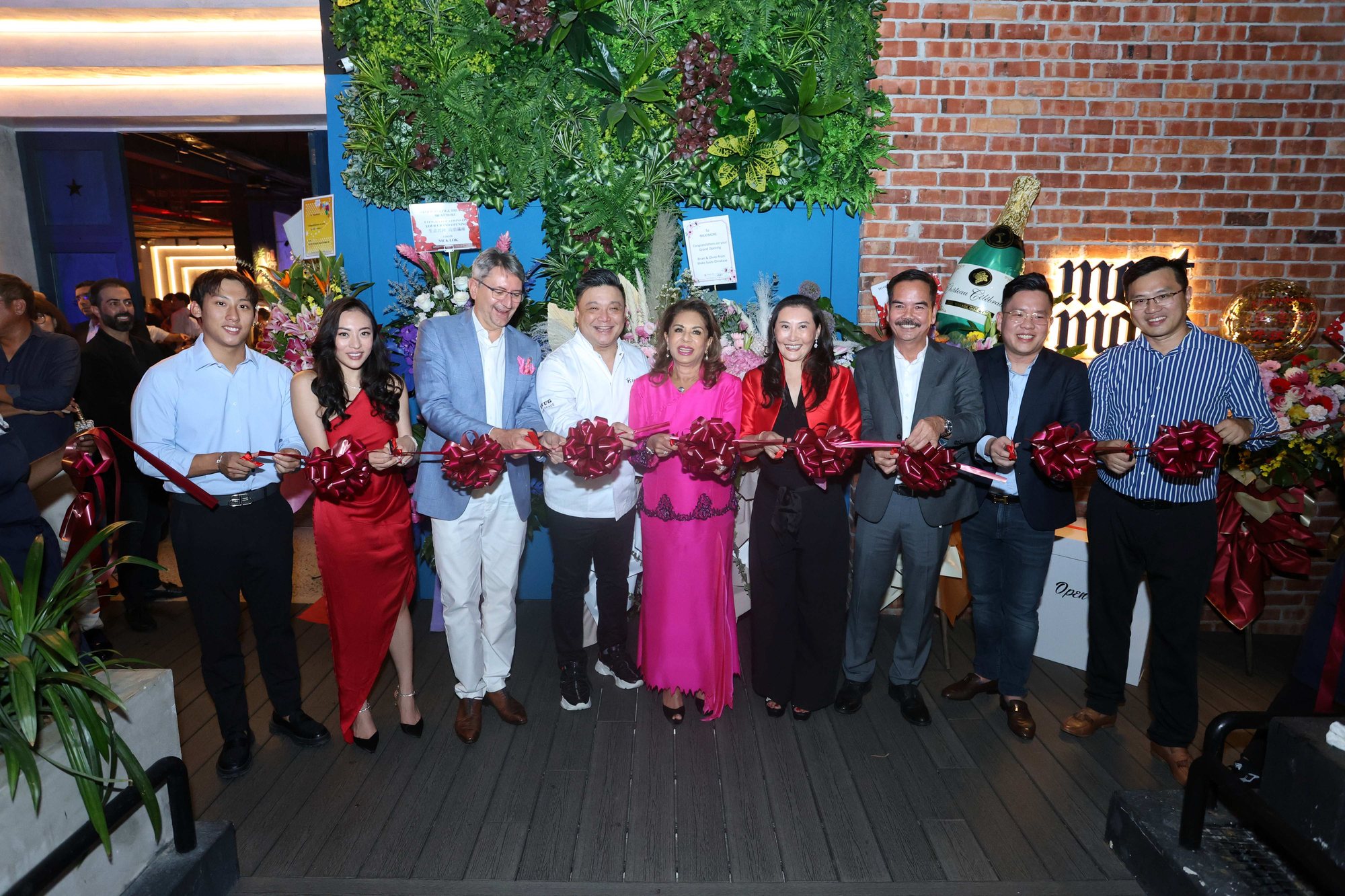 The ribbon cutting at the MeatMore grand opening: guests in a line across the entrance, each holding the red ribbon.