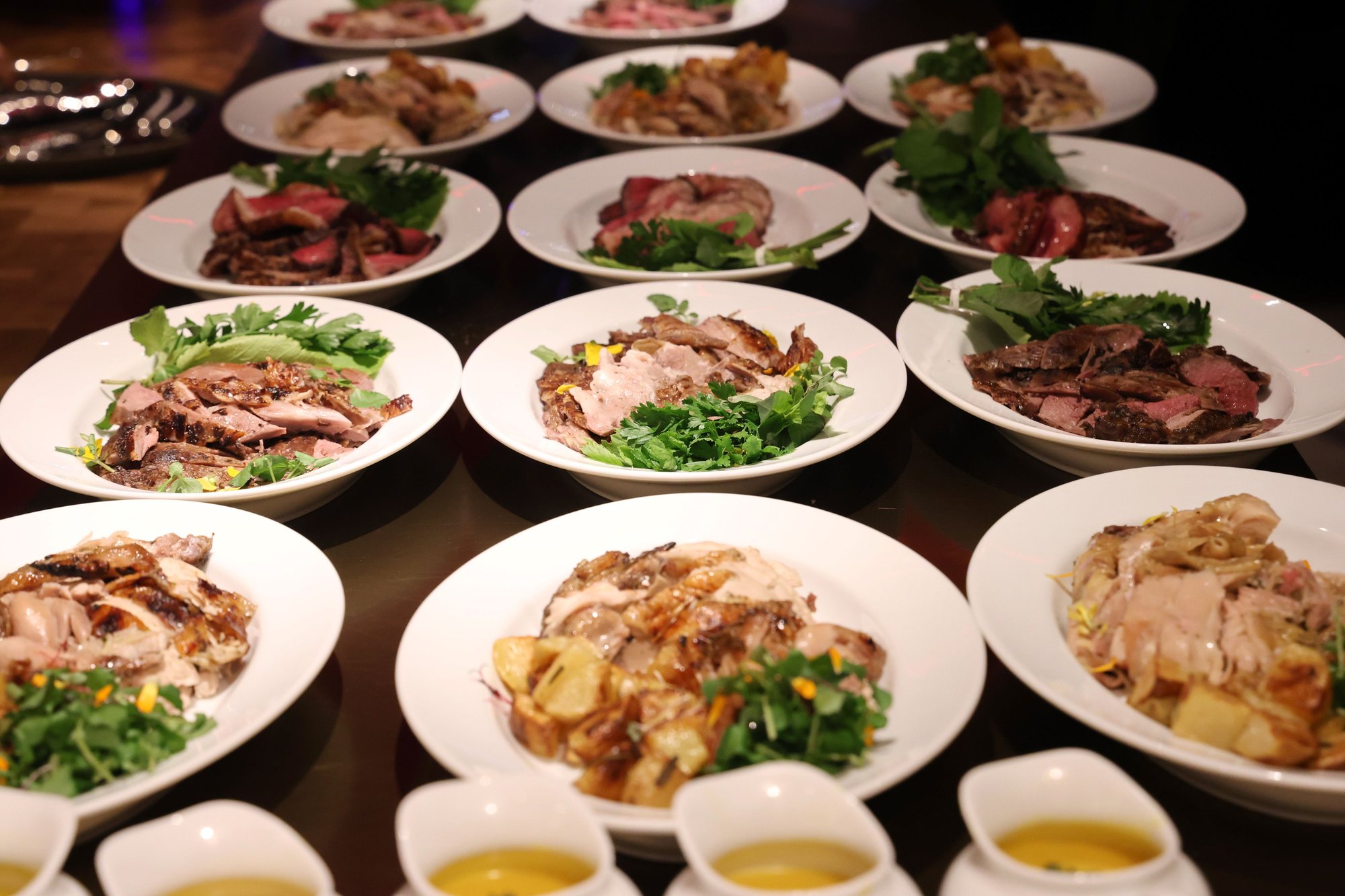 A table covered in plates of sliced meats, salads and sides.
